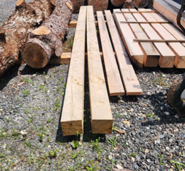 A pile of logs and wood sitting on gravel.