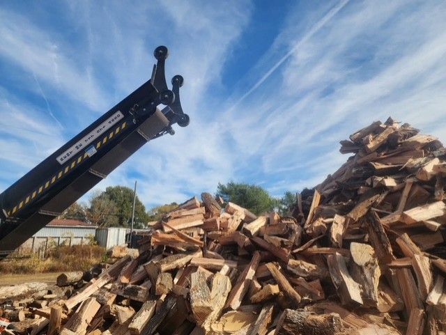 A pile of logs is being lifted by a crane.