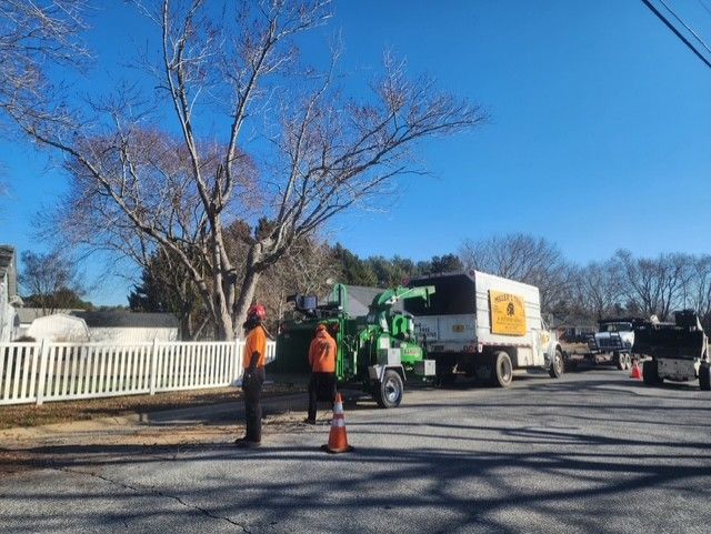 A group of men are standing in front of a tree chipper.