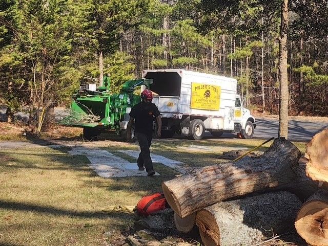 A man is walking in front of a tree chipper truck.