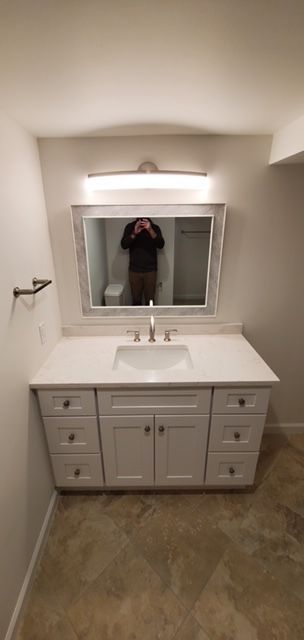 A bathroom with a sink, mirror, and cabinets