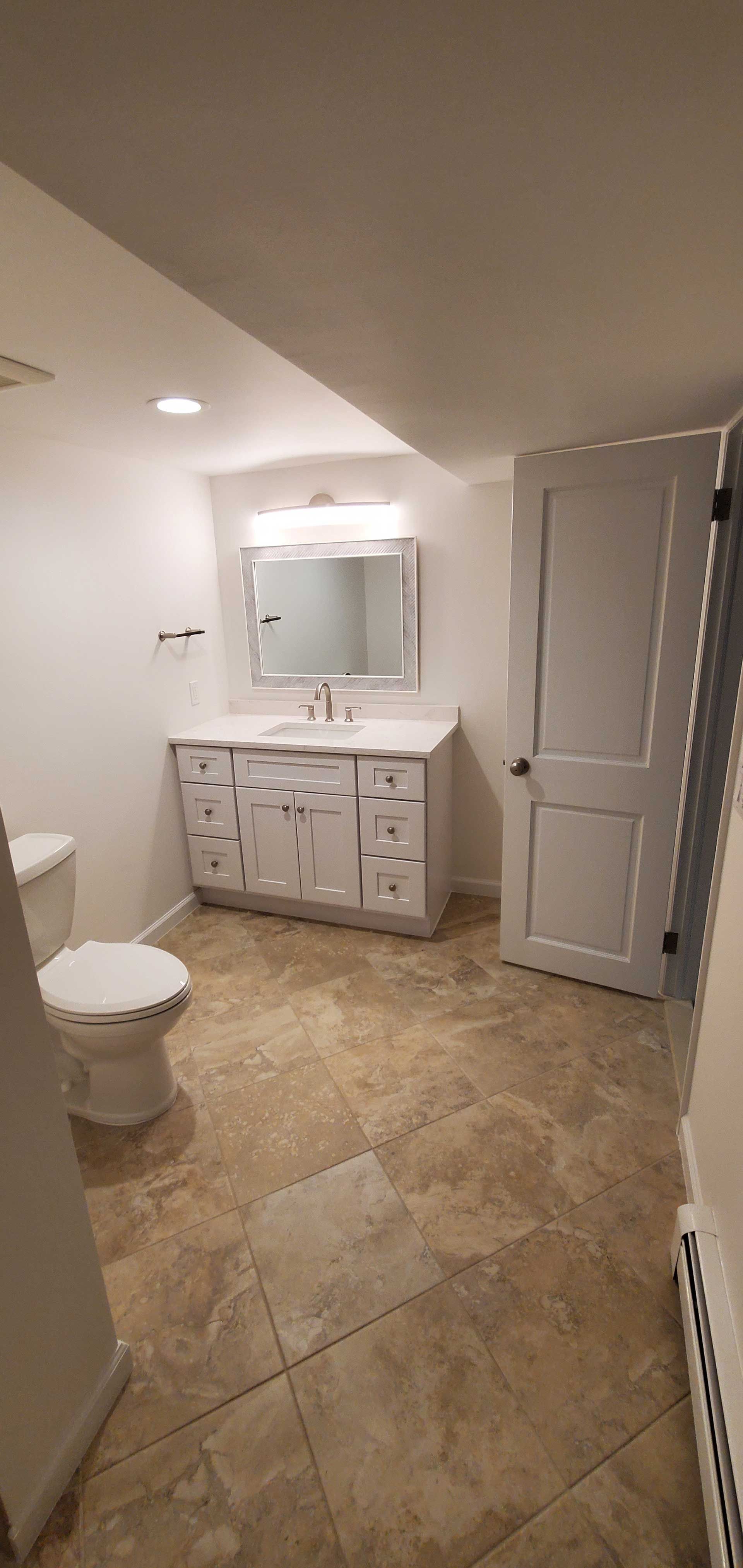 A spacious bathroom with a toilet, sink, and mirror