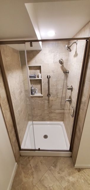 A bathroom with a walk-in shower and a glass door