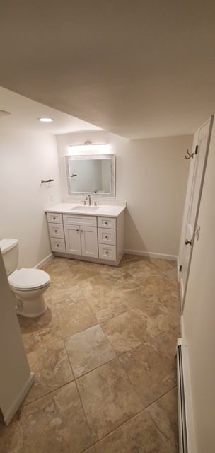 A bathroom with a toilet, sink, and mirror