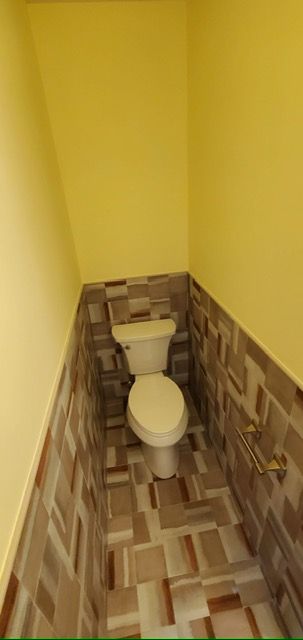A bathroom with a toilet and yellow walls