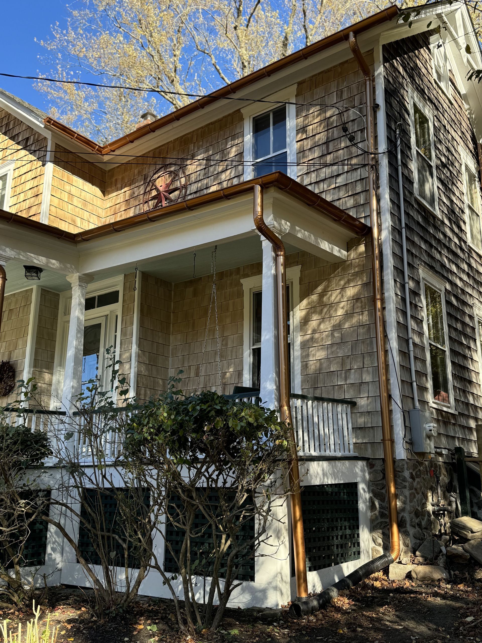A large house with a porch and a gutter on the side of it.