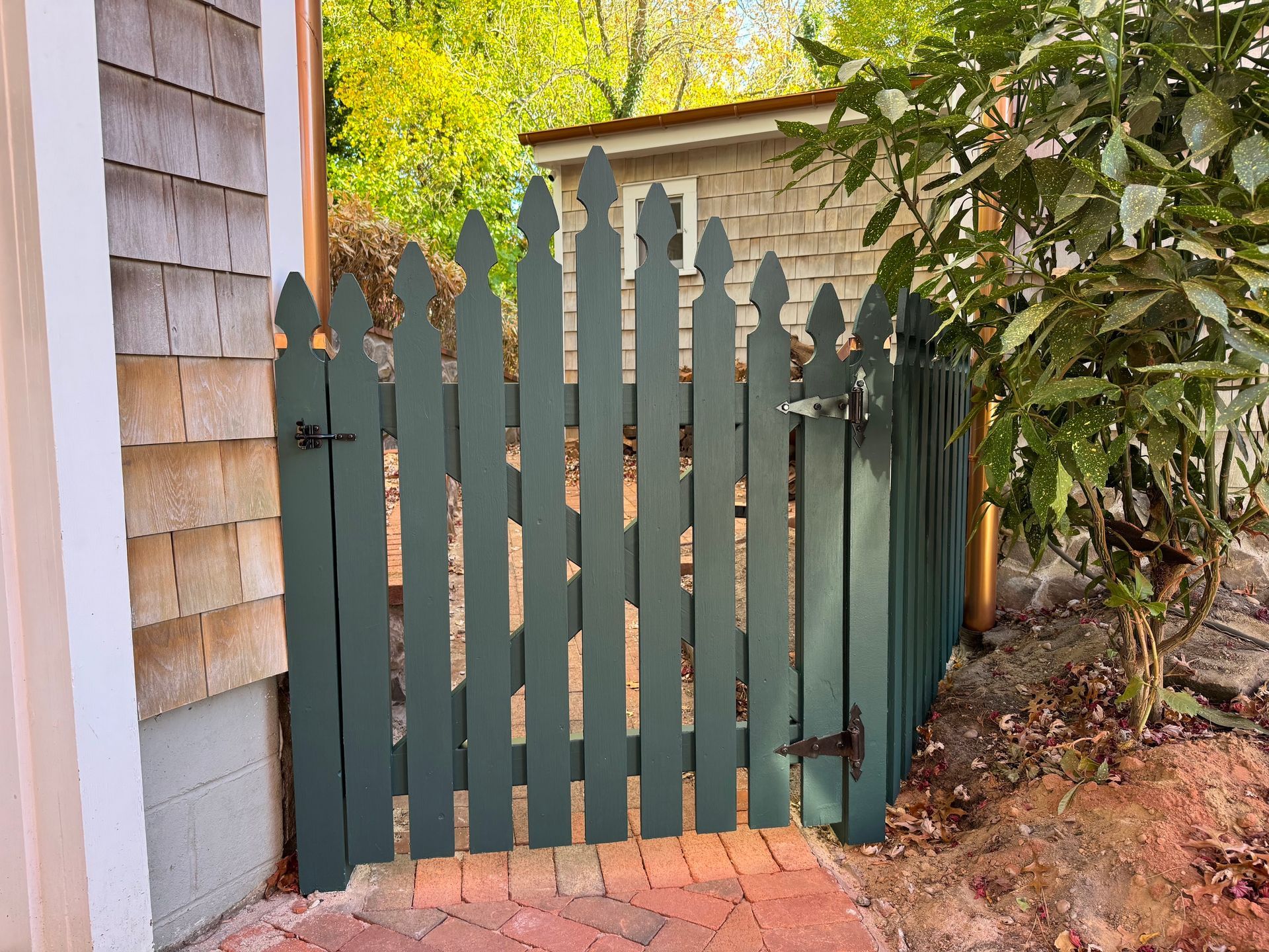 A green picket fence is next to a brick walkway.