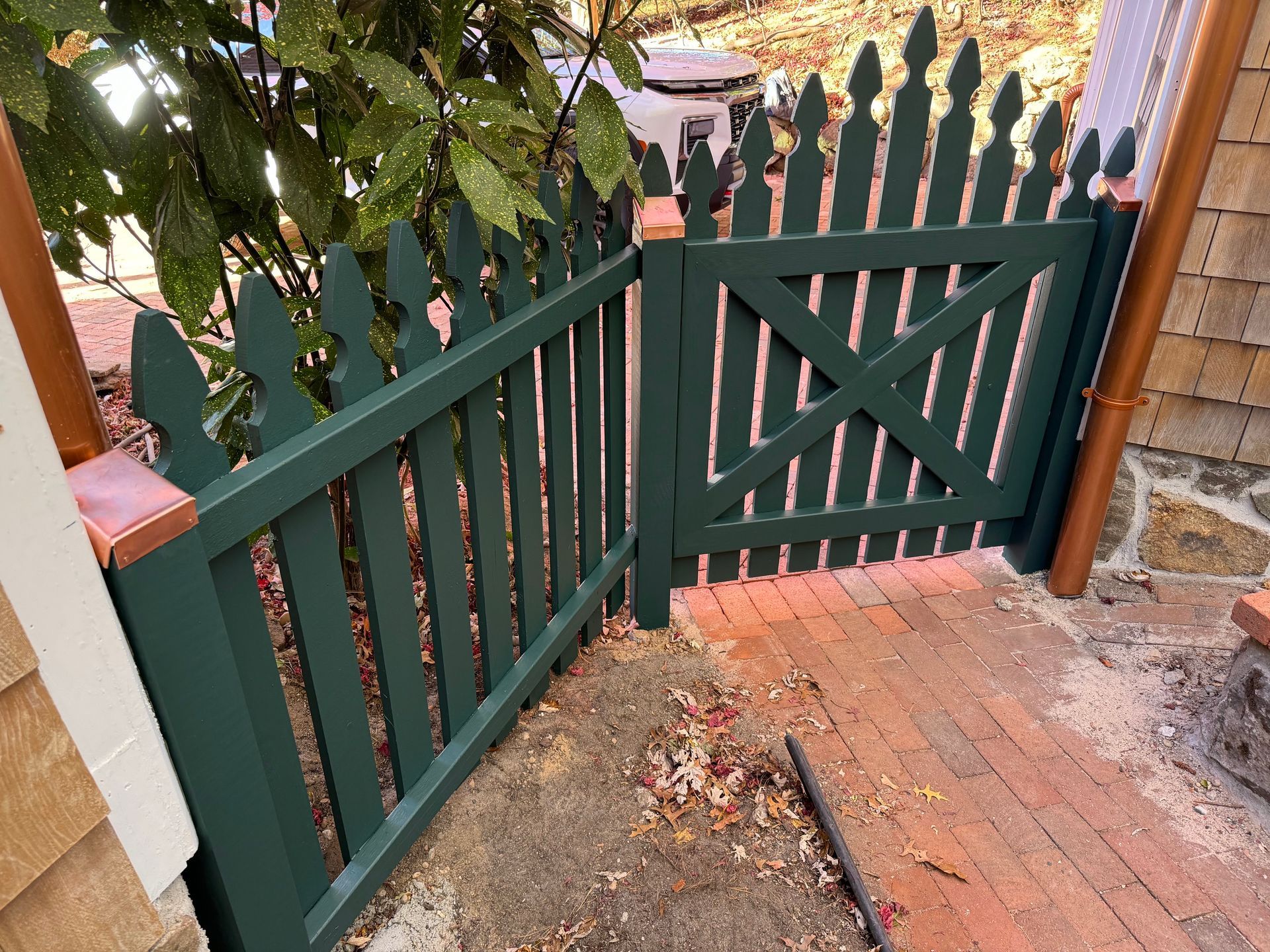 A green picket fence with a gate leading to a brick walkway.
