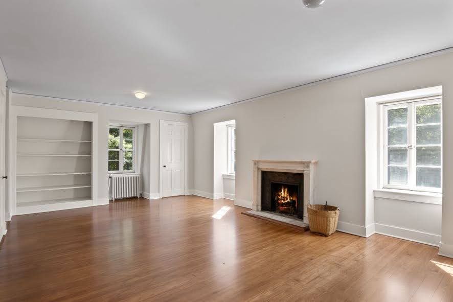 An empty living room with hardwood floors and a fireplace.