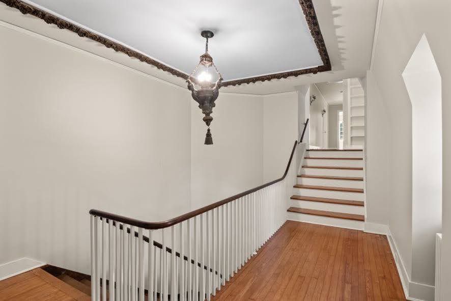 A hallway with stairs and a chandelier hanging from the ceiling.