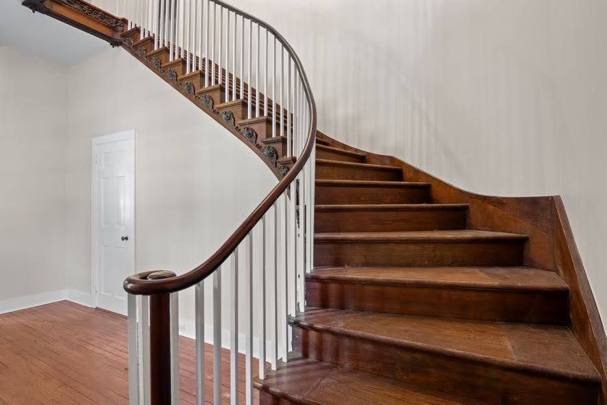 A wooden spiral staircase with a white railing in a house.