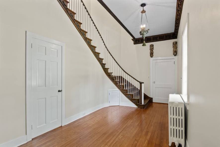 An empty hallway with a curved staircase and a radiator.