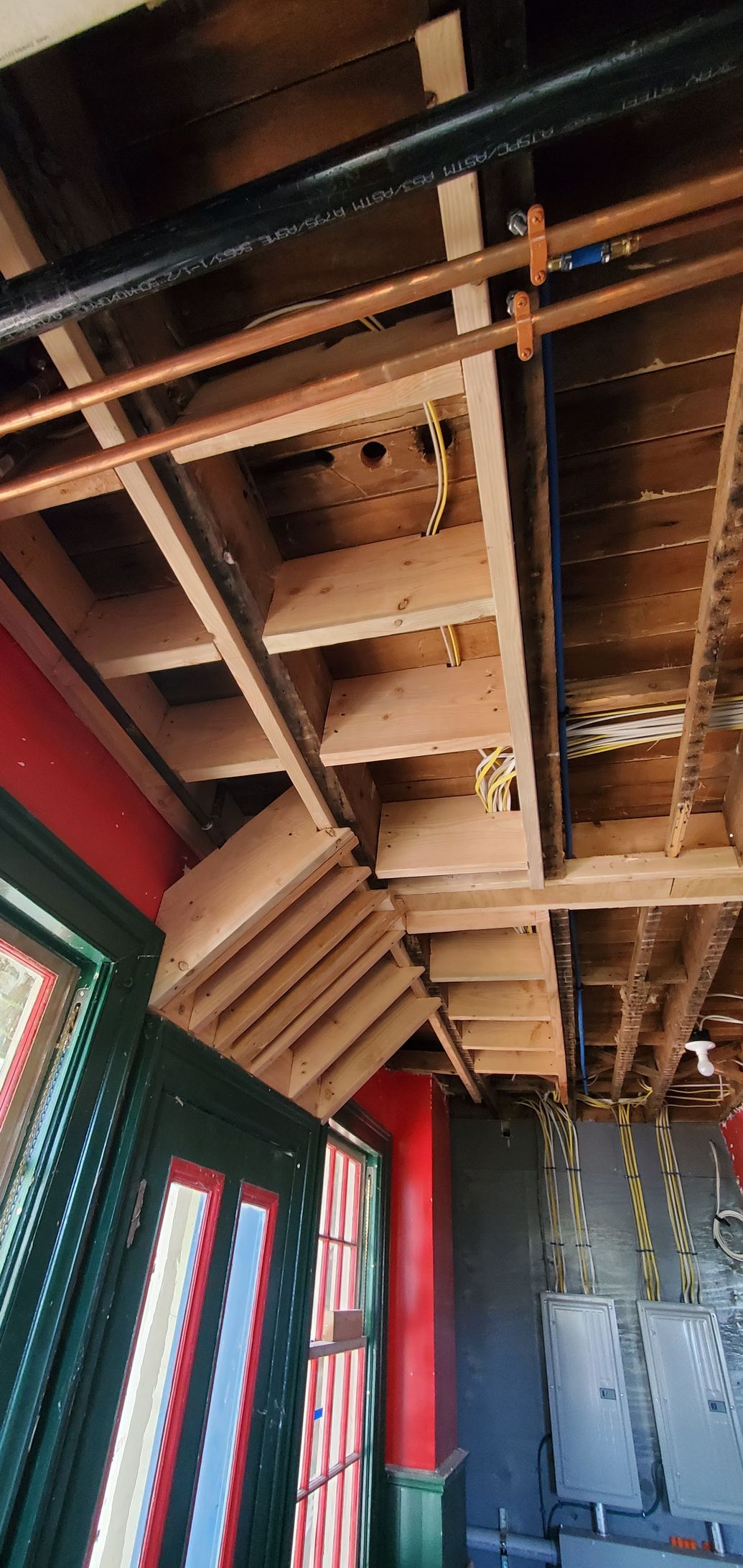 A wooden staircase is being built into the ceiling of a building.