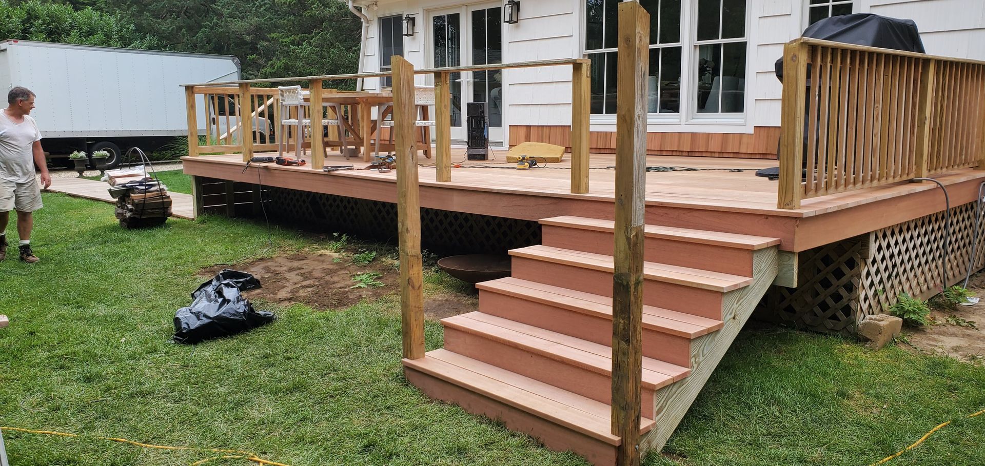 A man is standing in front of a wooden deck with stairs