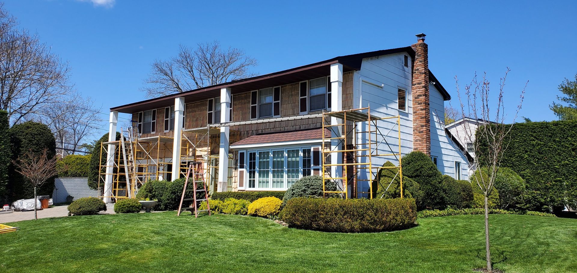 A large house with scaffolding in front of it is being painted