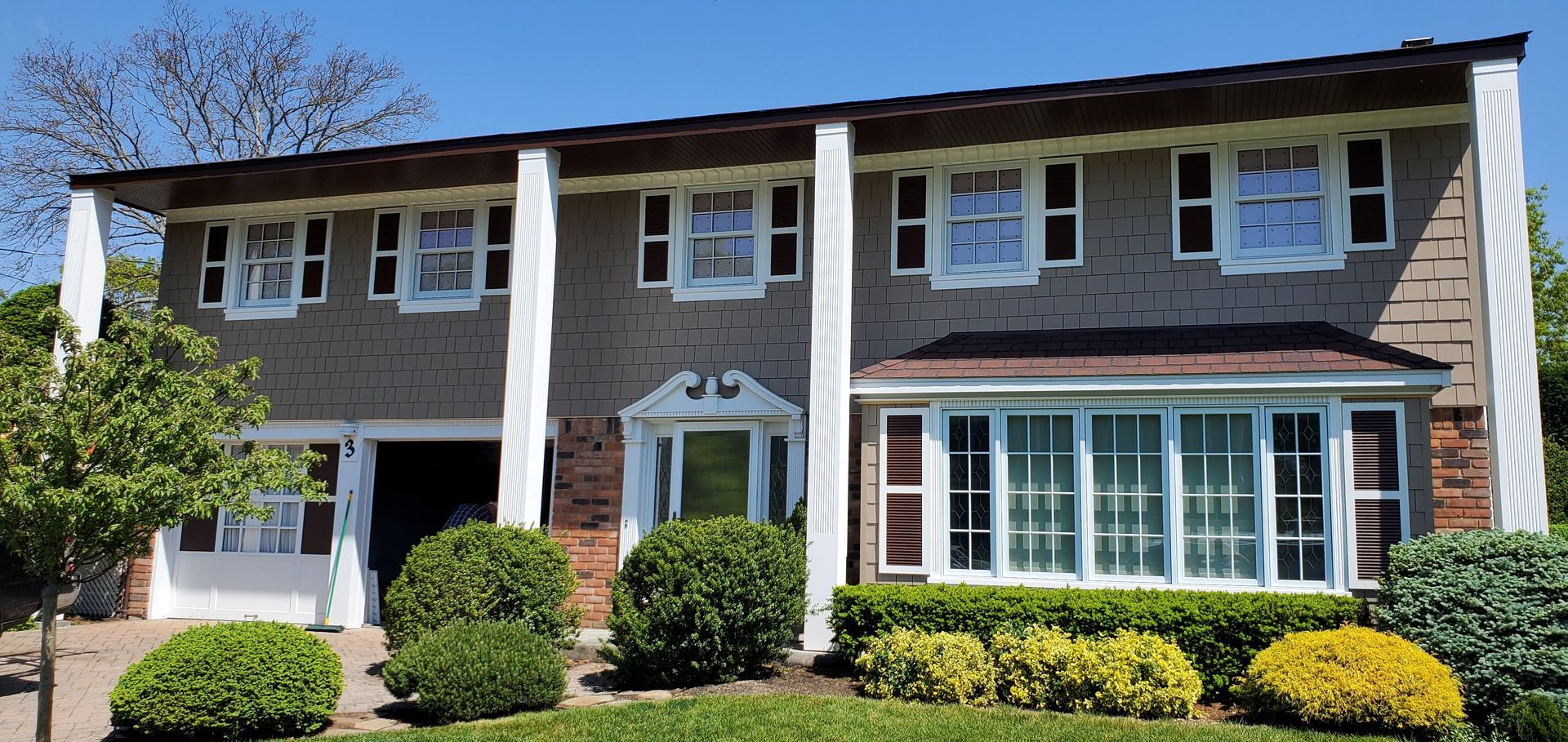 A large house with a lot of windows is surrounded by trees and bushes