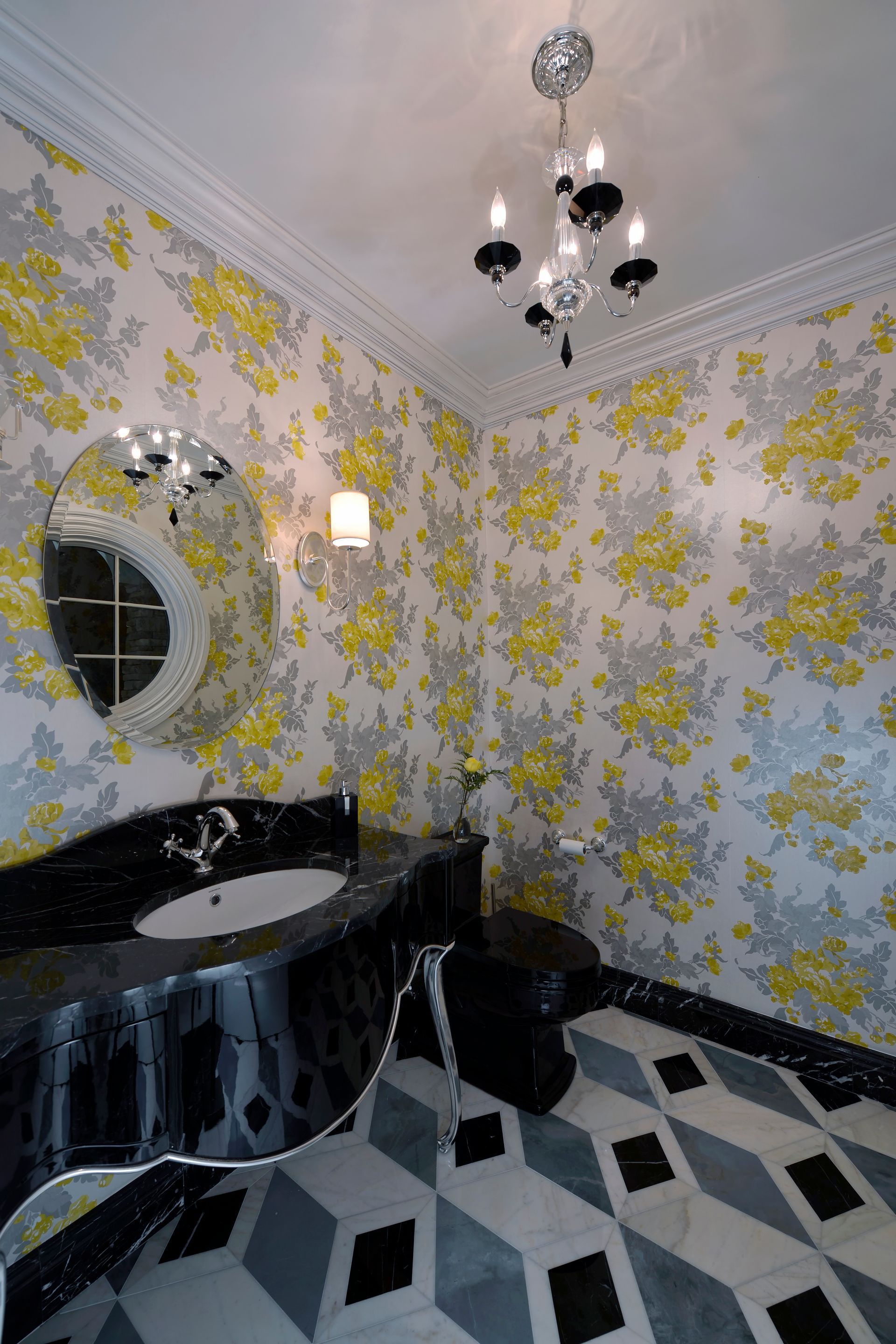 A bathroom with a sink, toilet, mirror, and chandelier