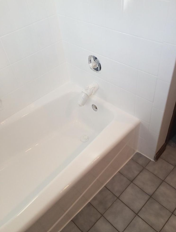 White bathtub with faucet in a tiled bathroom.