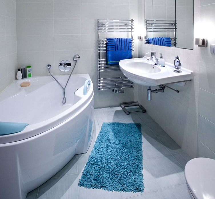 Modern white bathroom with blue accents. Bathtub, sink, and fluffy rug.