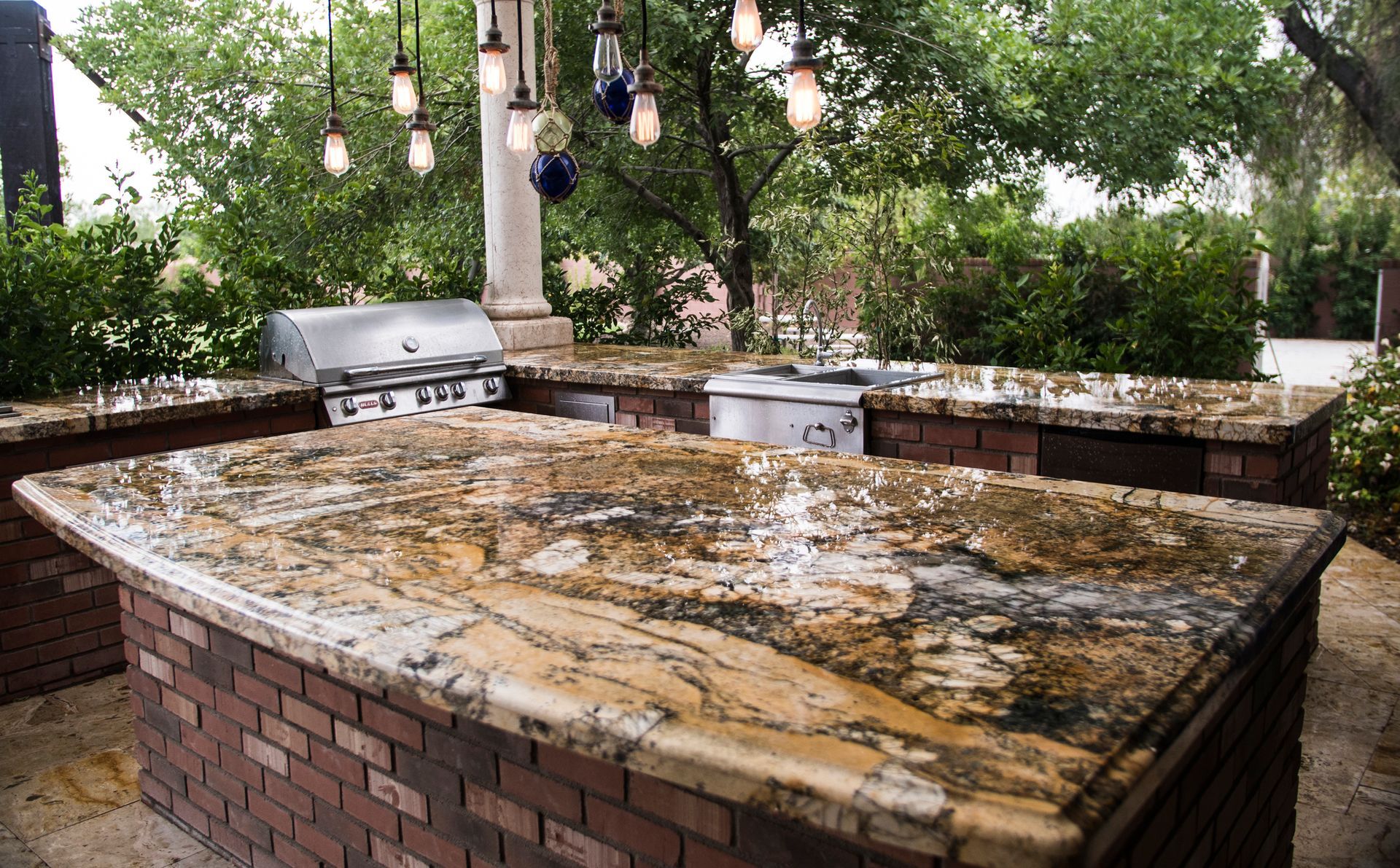 A patio with a couch , chairs , ottoman , table and bar.