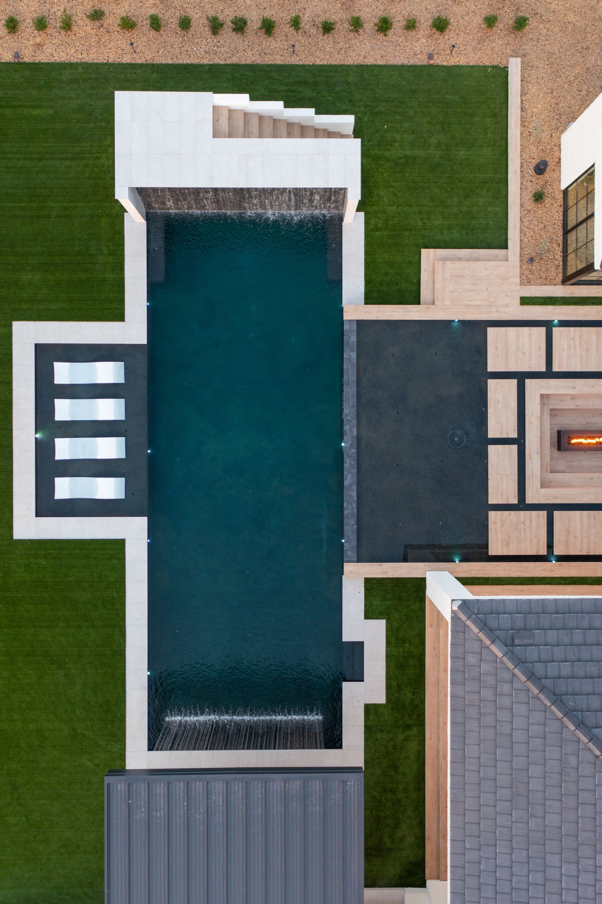 An aerial view of a large swimming pool in the backyard of a house.