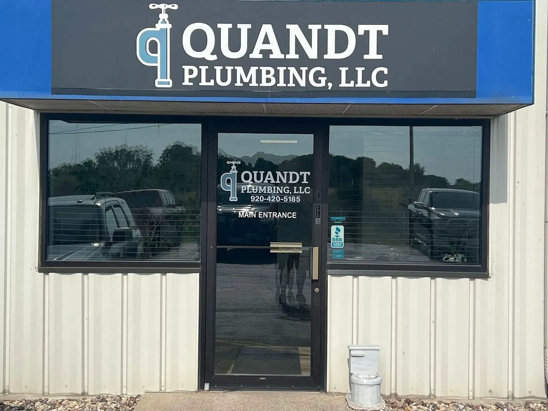 Exterior of Quandt Plumbing LLC storefront with signage and door.