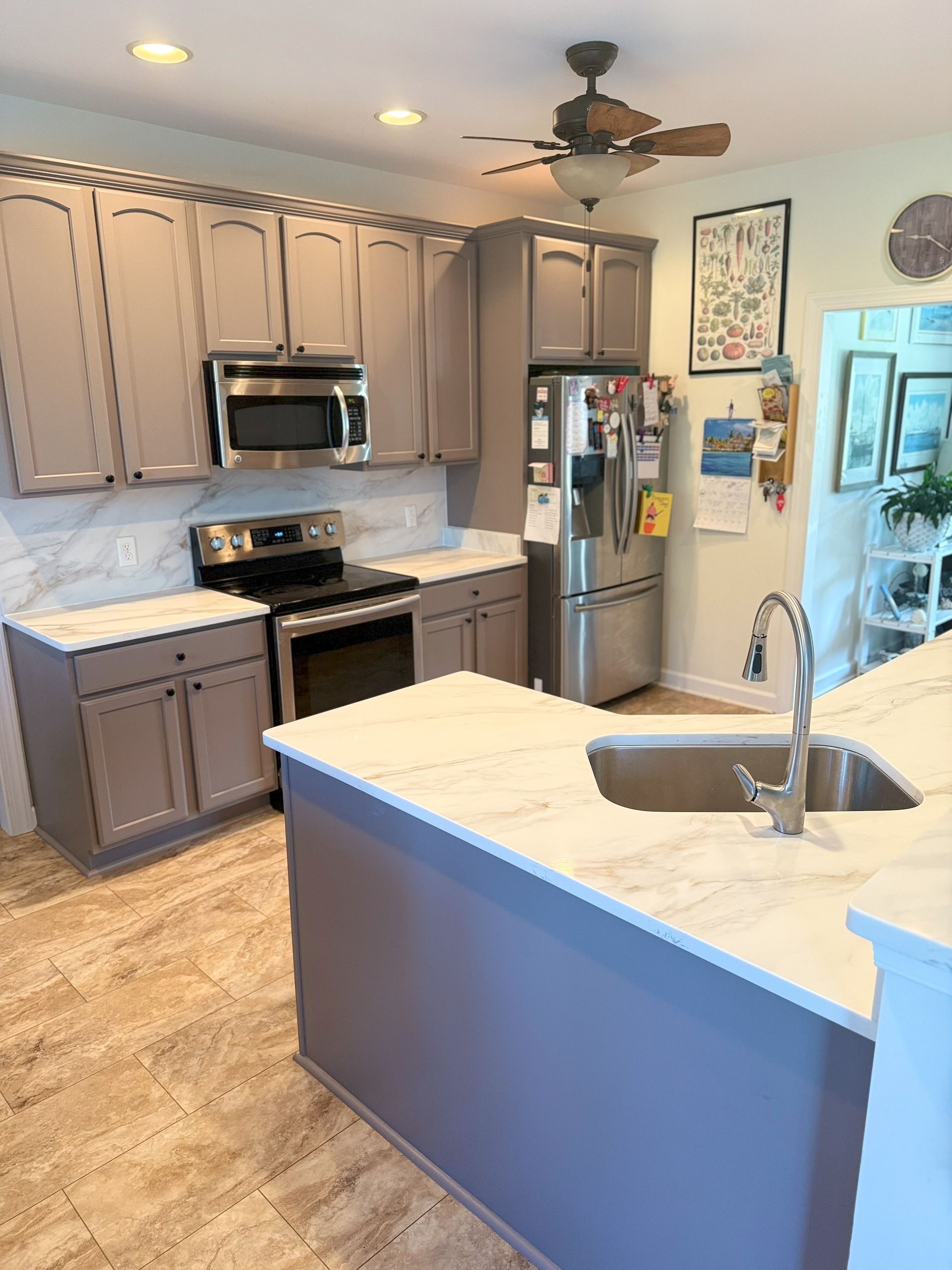 Kitchen with gray cabinets, white countertops, stainless steel appliances, and a large island.