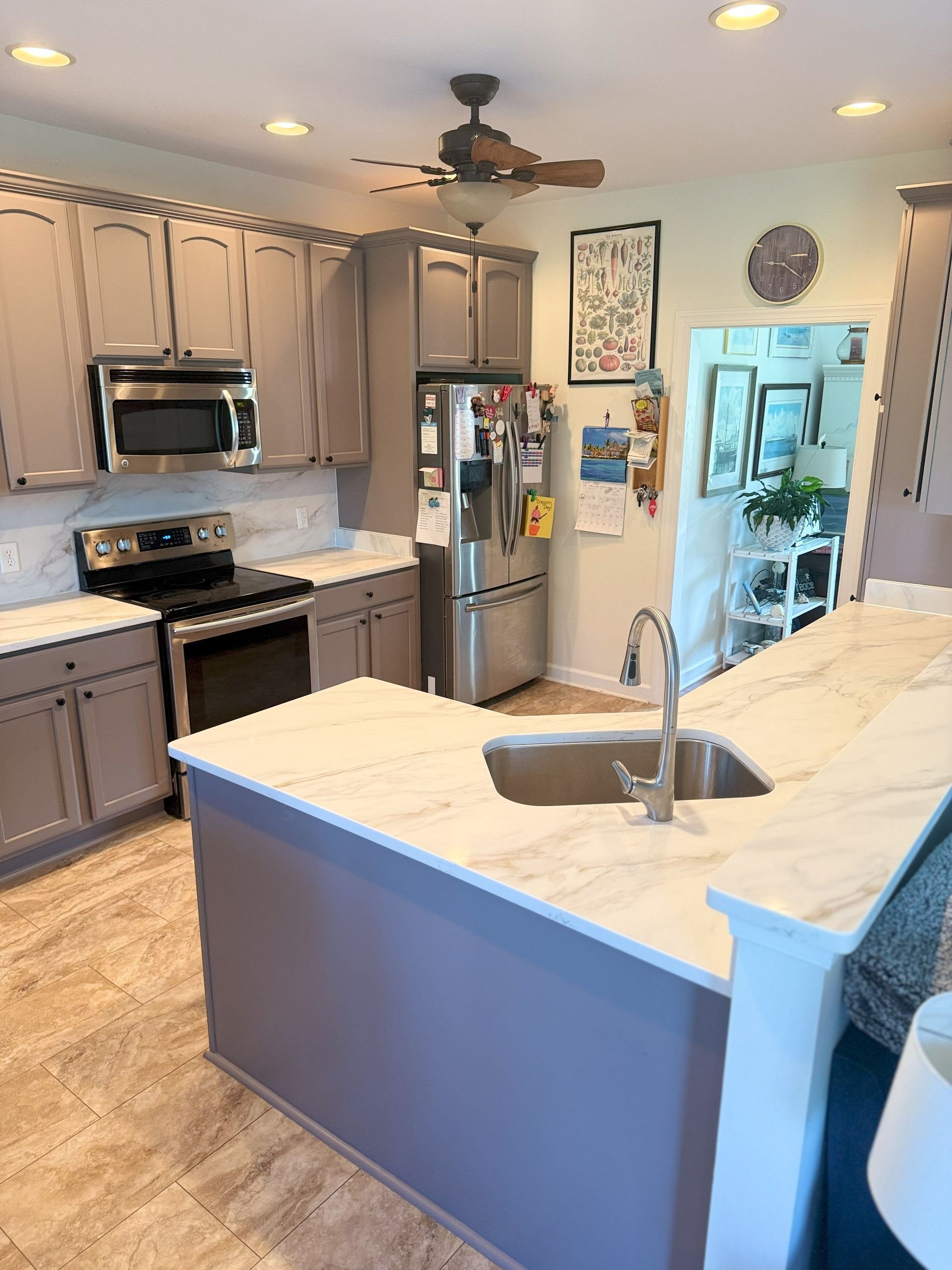 Gray and white kitchen with stainless steel appliances, island, and doorway.