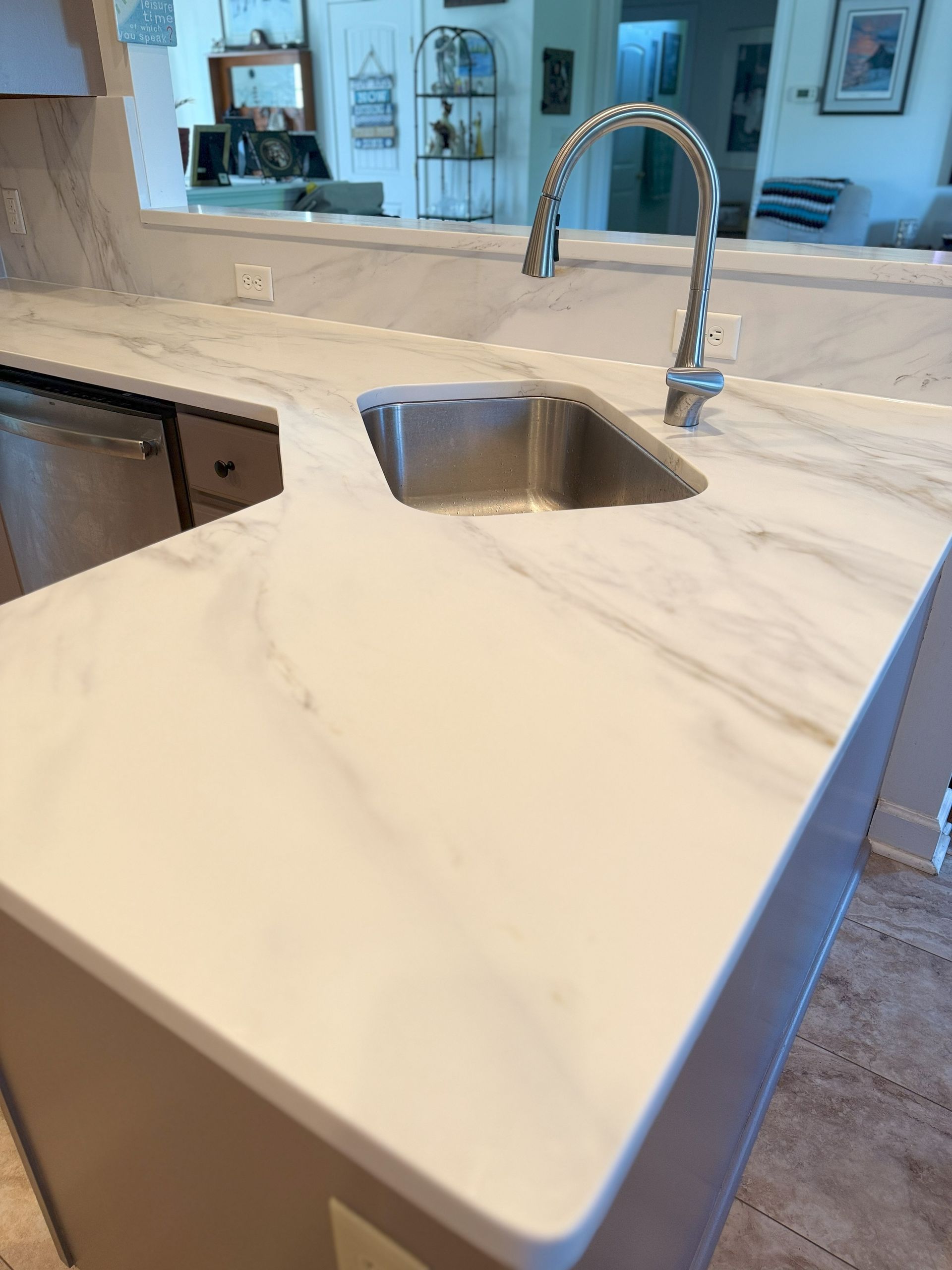 White marble countertop with stainless steel sink and faucet.