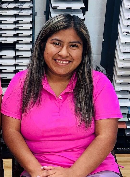 A woman in a pink shirt is smiling for the camera.