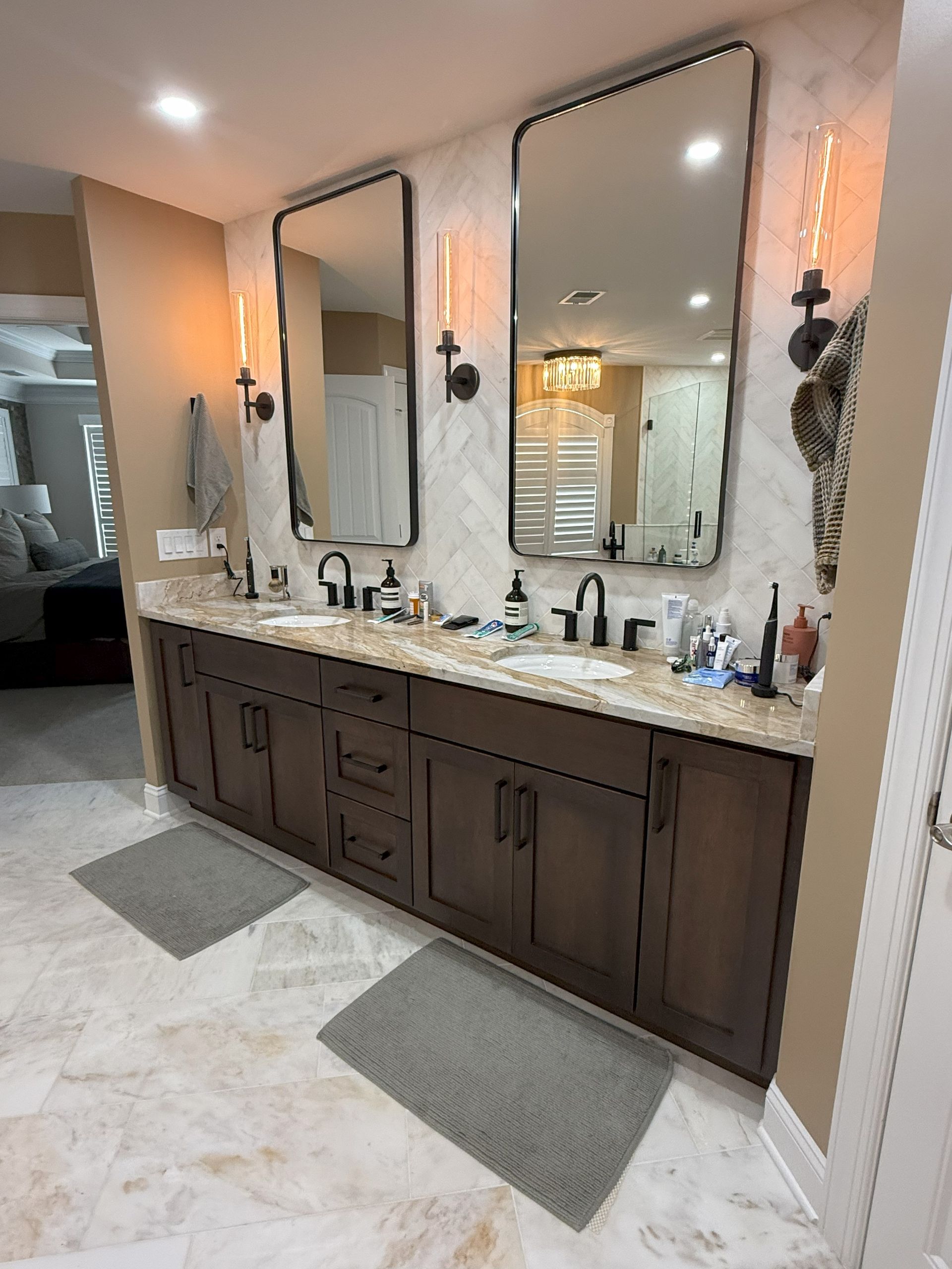 Bathroom with a dark wood vanity, two mirrors, and stone tile.