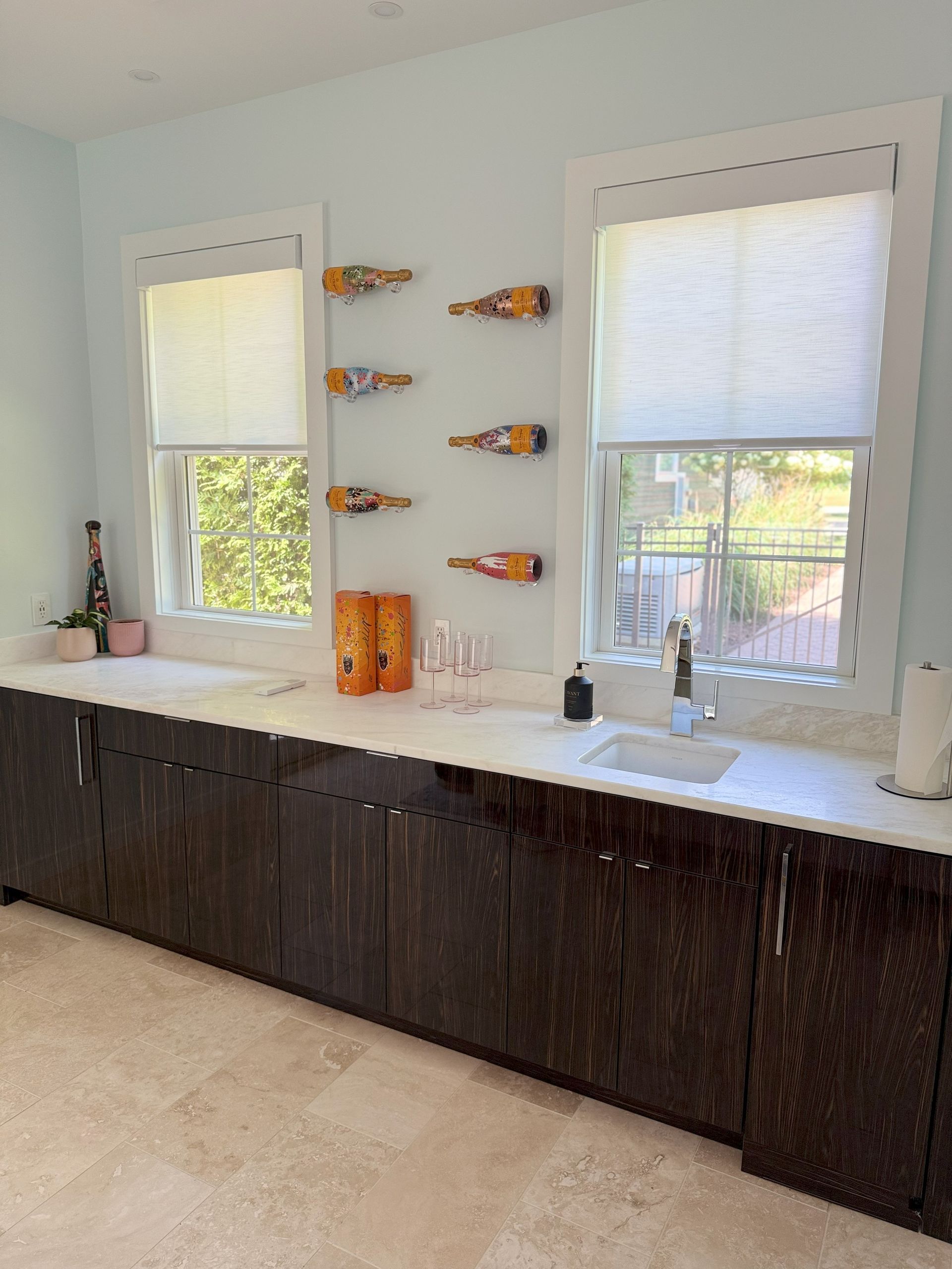Bar area with dark cabinets, white countertop, two windows, and wine rack.