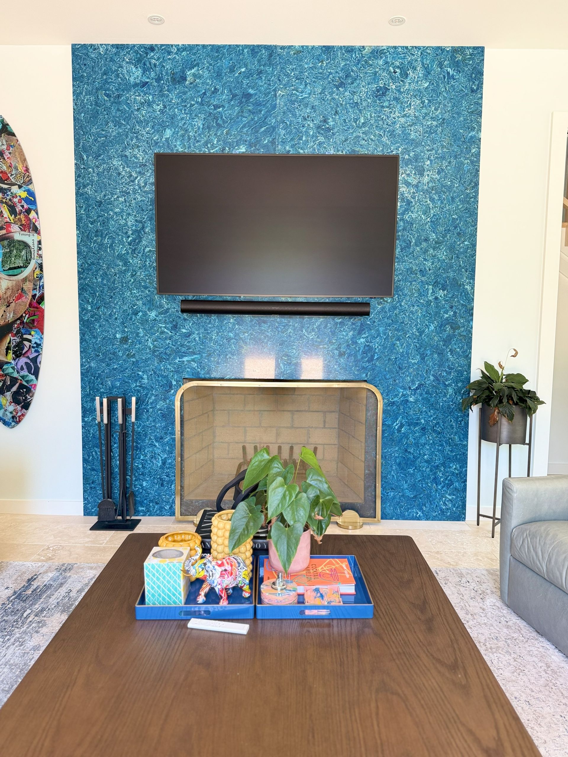 Living room with blue sparkly fireplace, TV, coffee table with tray, and a surfboard.