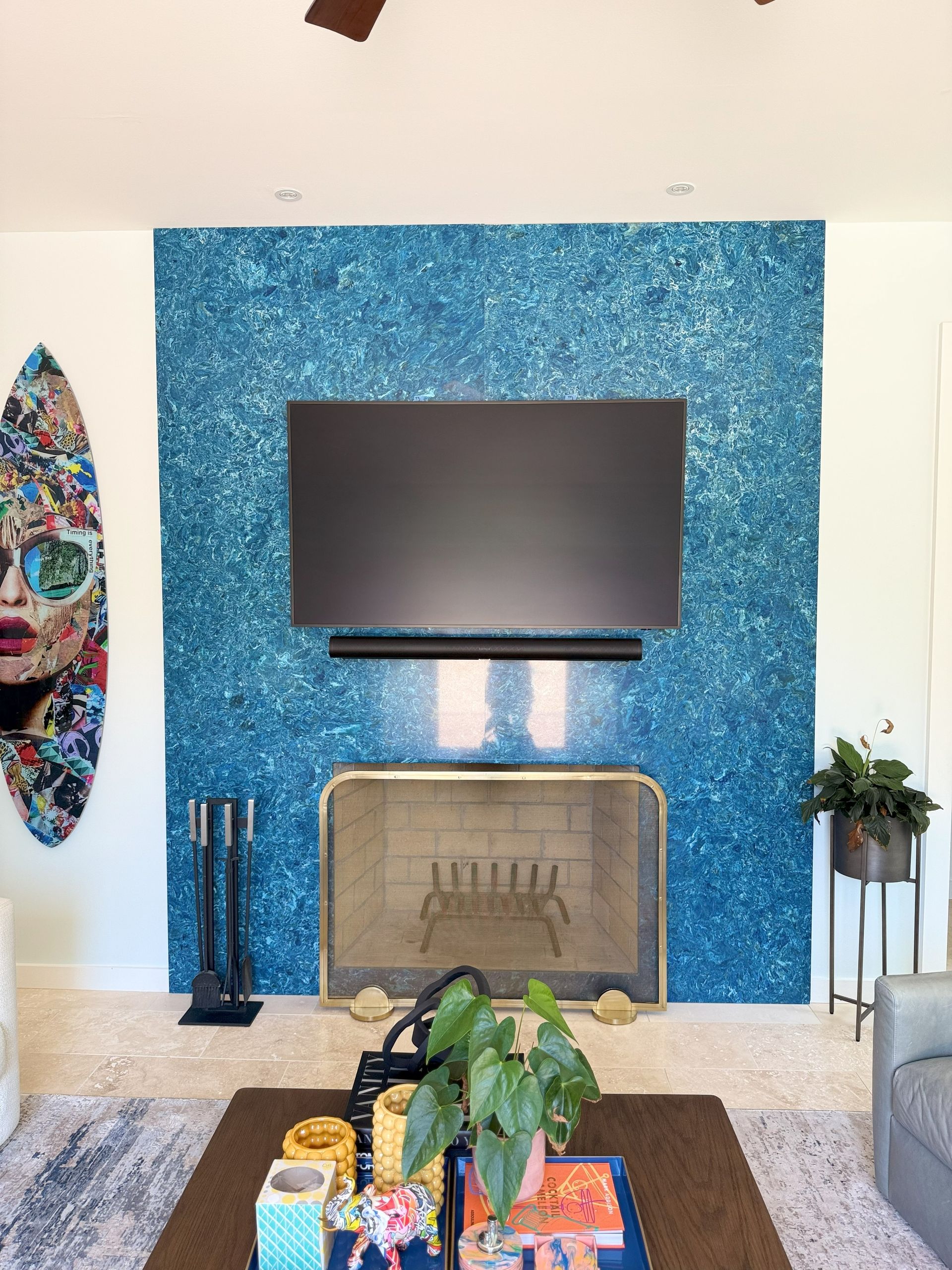 Living room with blue sparkly fireplace surround, TV, and surfboard art.