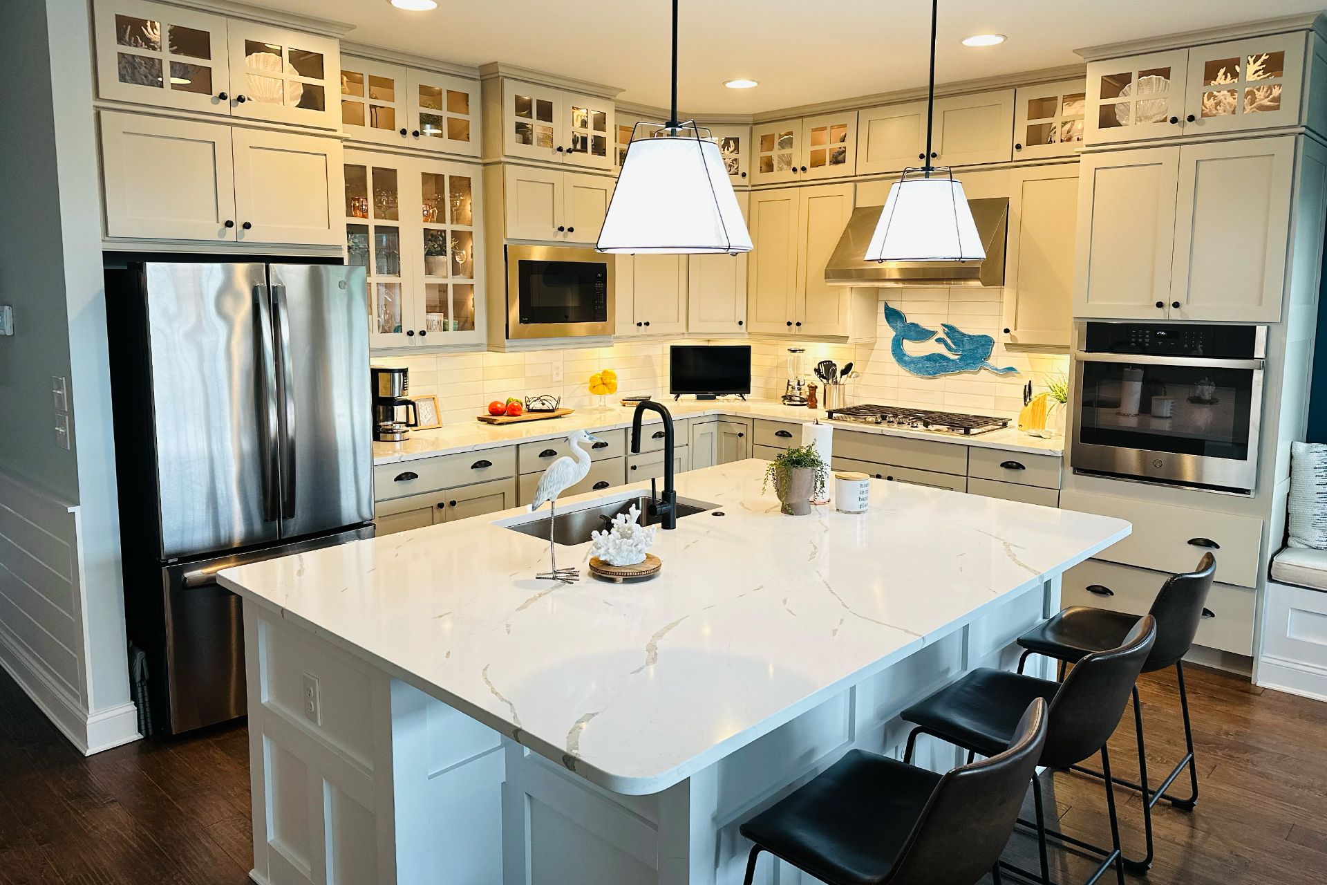A kitchen with white cabinets, stainless steel appliances, and a large island.