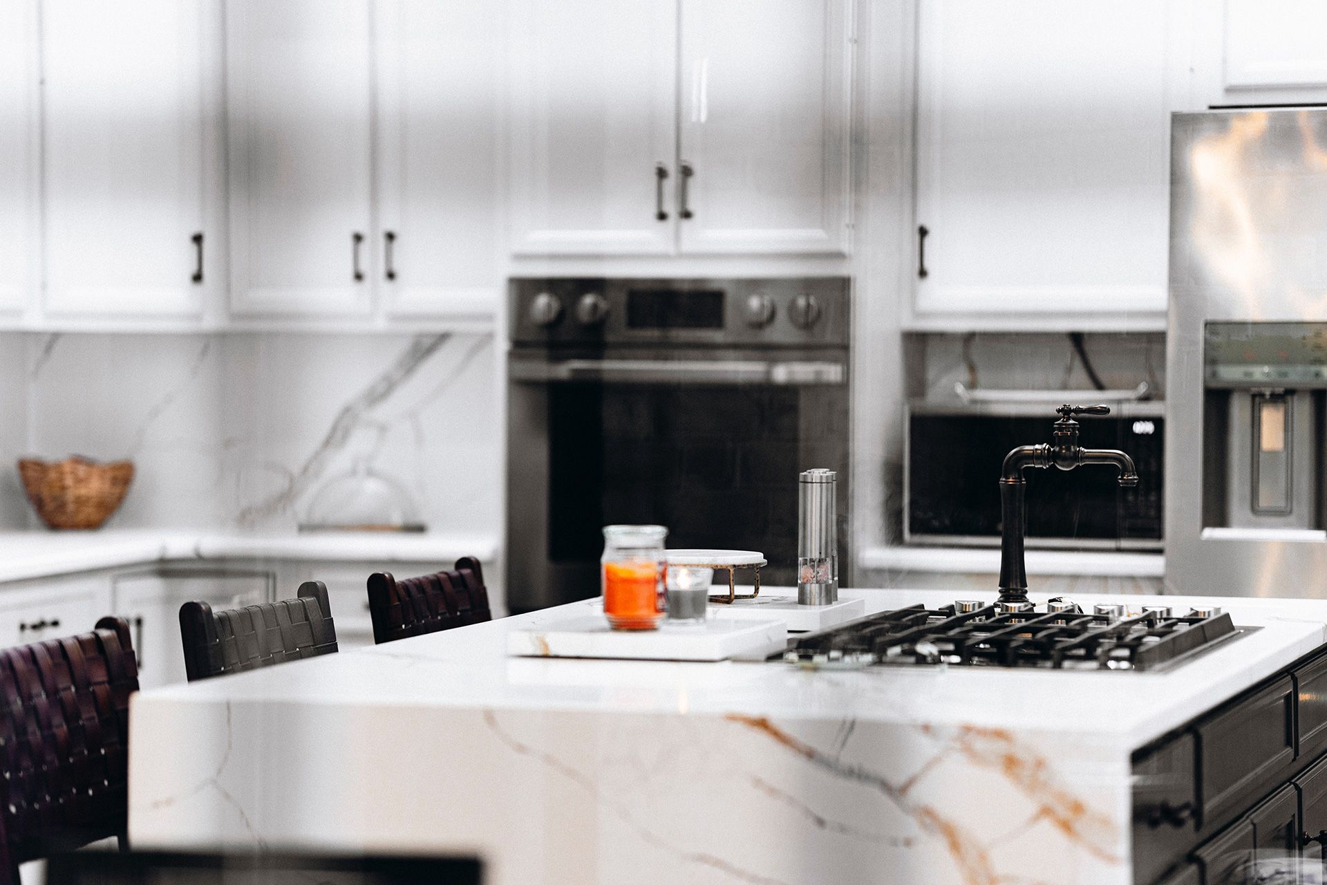 A kitchen with white cabinets, stainless steel appliances, and a marble counter top.
