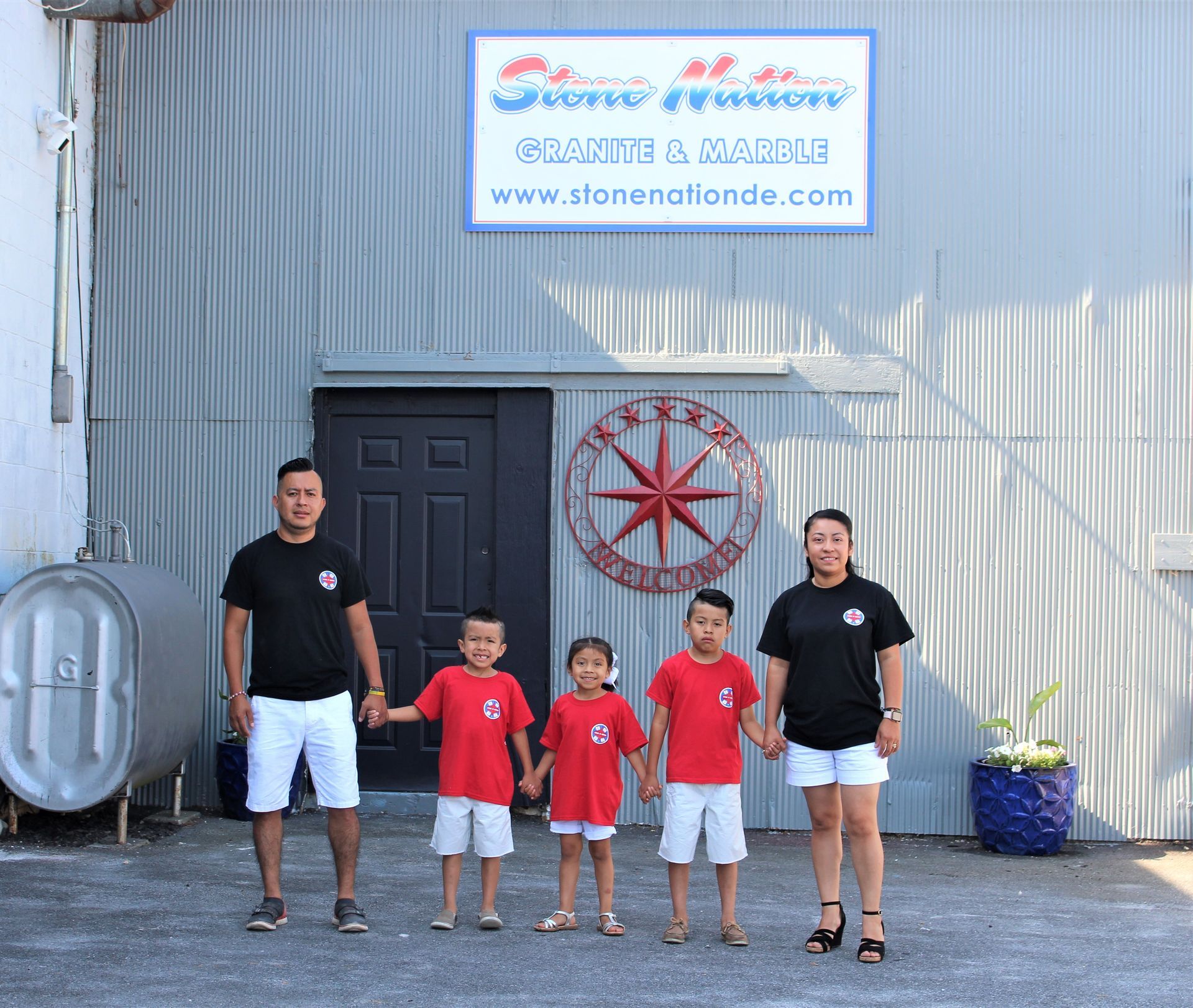 A group of people standing in front of a building with a welcome sign - before