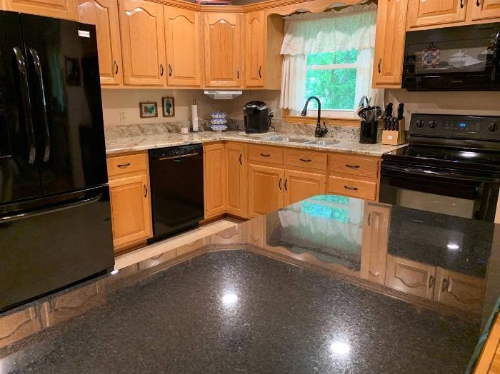 A kitchen with wooden cabinets , black appliances and a black refrigerator