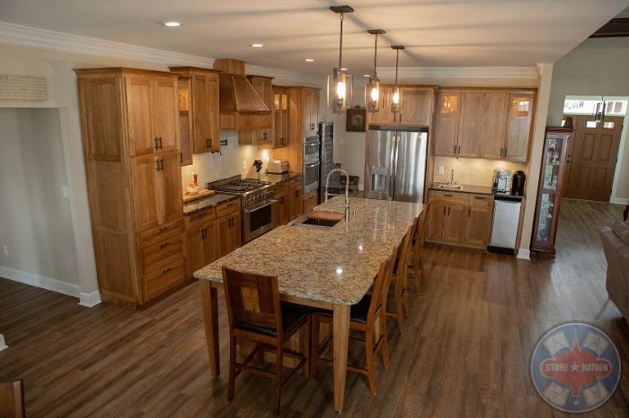 A kitchen with wooden cabinets , granite counter tops , stainless steel appliances and a large island.