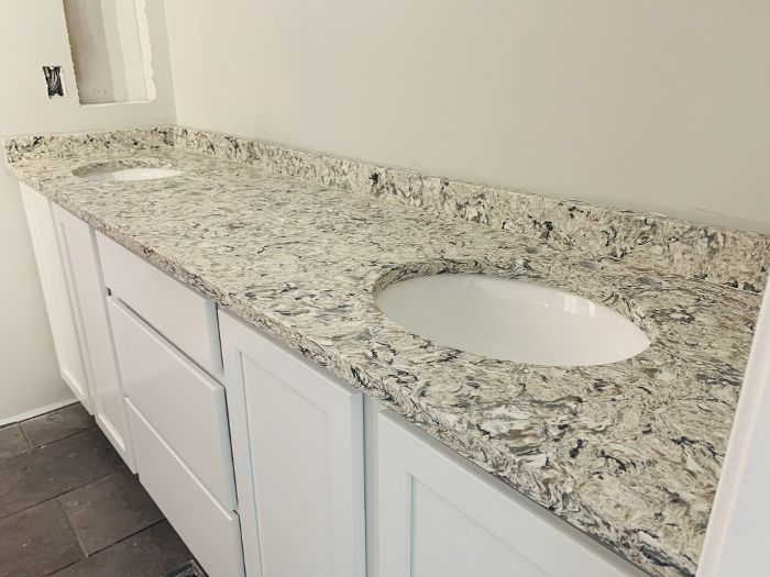 A bathroom with two sinks and granite counter tops.