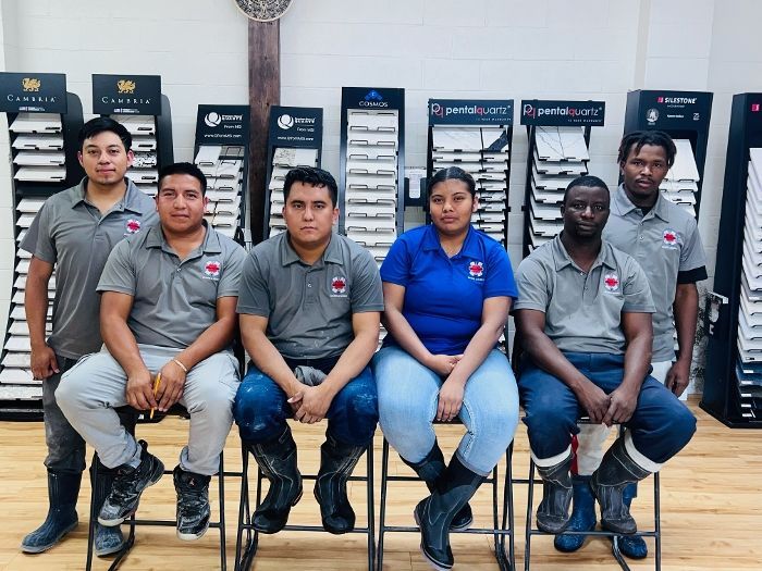 A group of people are posing for a picture while sitting on stools