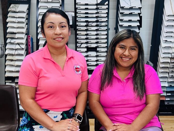 Two women in pink shirts are sitting next to each other in a room.