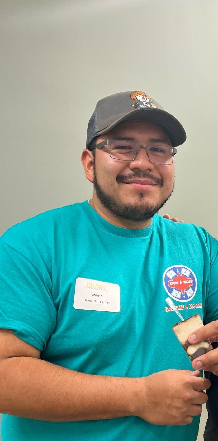 A man with a beard and glasses is wearing a hat and a blue shirt.