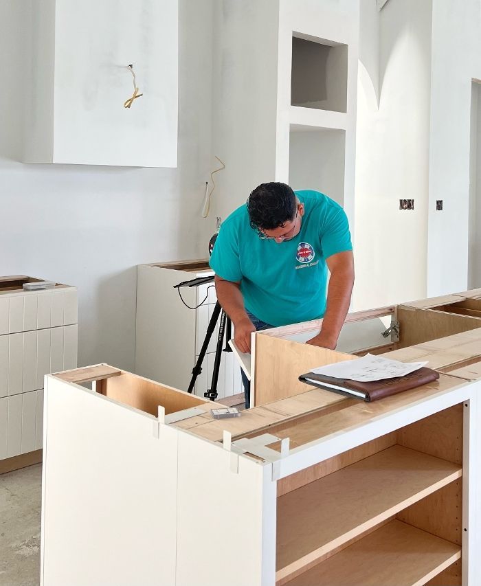 A man in a blue shirt is working on a kitchen island.