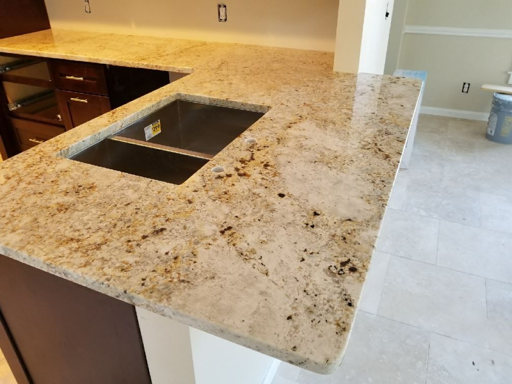 A kitchen with granite counter tops and a stainless steel sink.