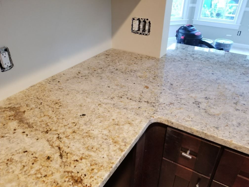 A kitchen with a granite counter top and dark cabinets