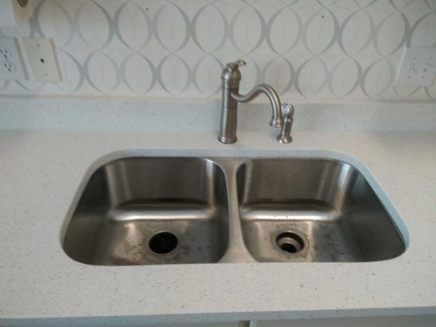 A stainless steel kitchen sink with two sinks and a faucet