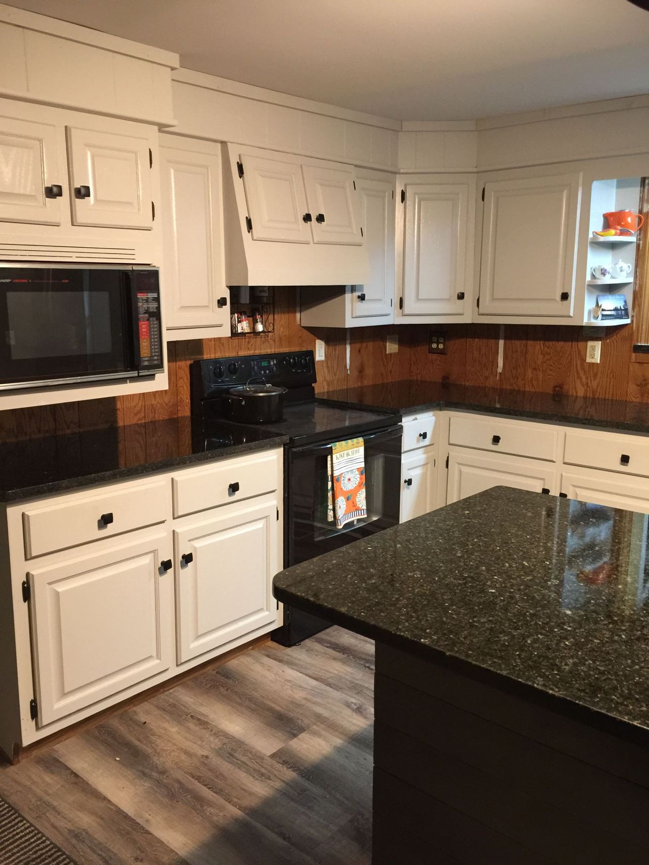 A kitchen with white cabinets and black counter tops
