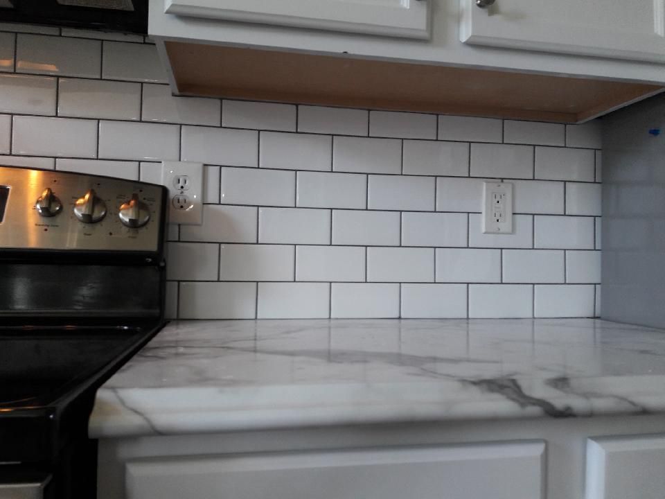 A kitchen with a stove and a counter top with white tiles.