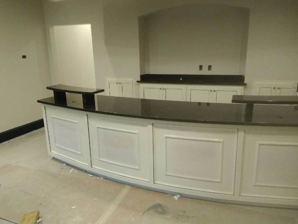 A kitchen with black counter tops and white cabinets